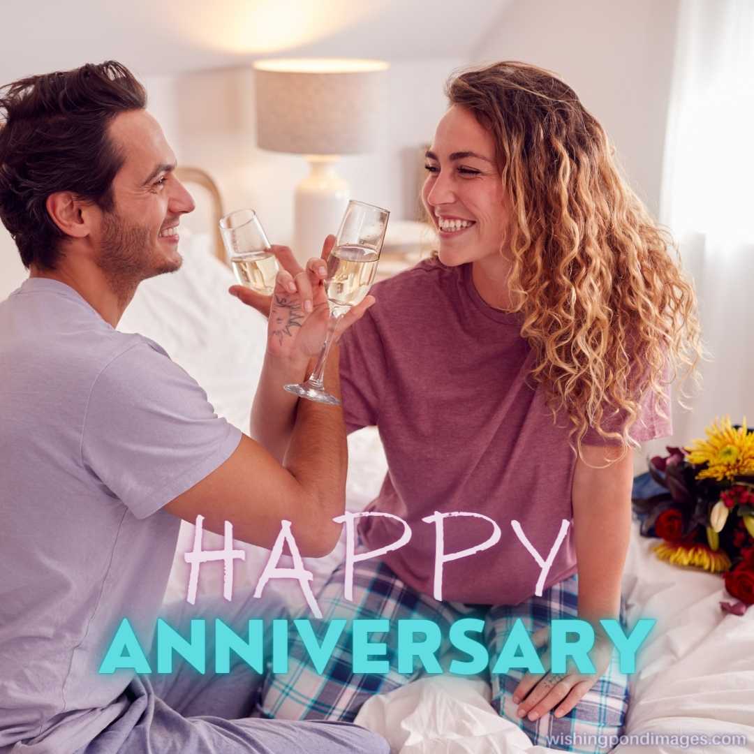 Loving Couple Wearing Pyjamas In Bed At Home Celebrating Anniversary With Champagne