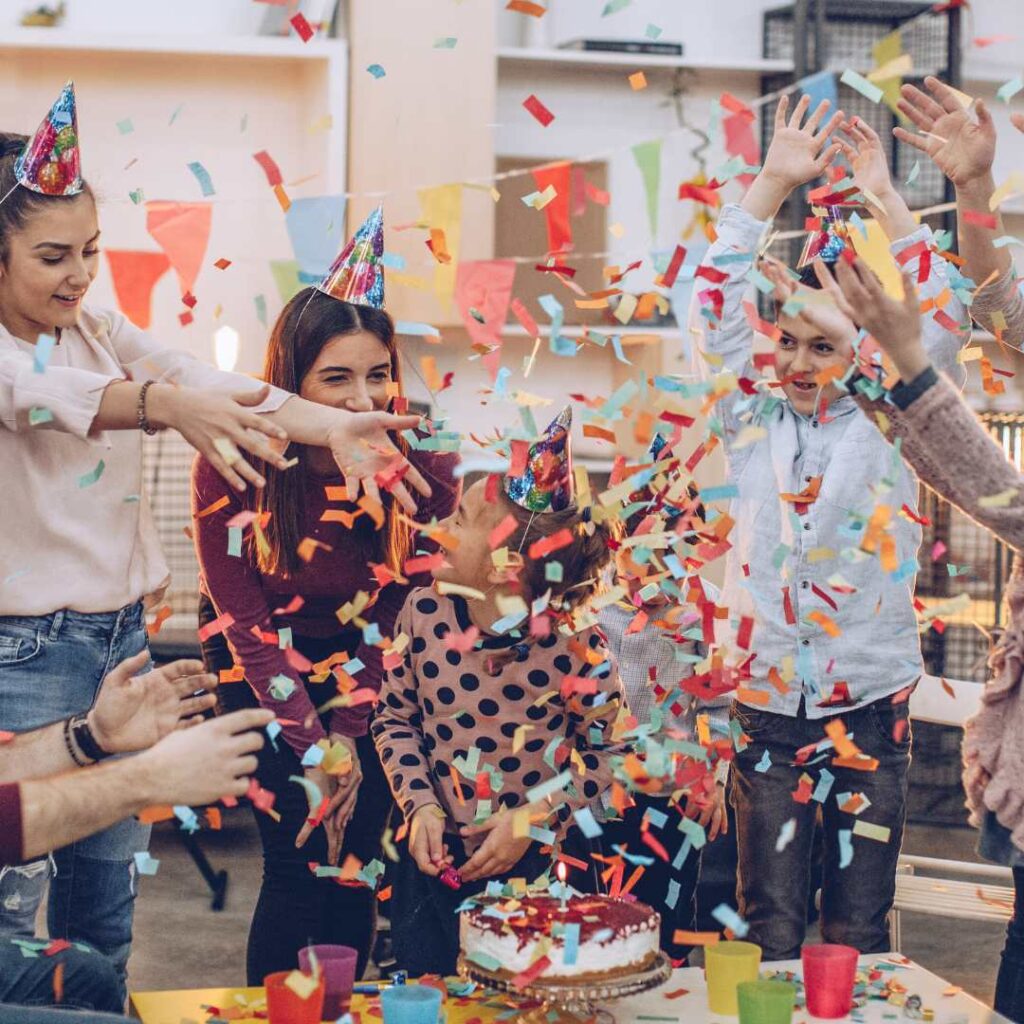 Happy young people celebrate birthdays with their friends at home, sitting at the dining table with 