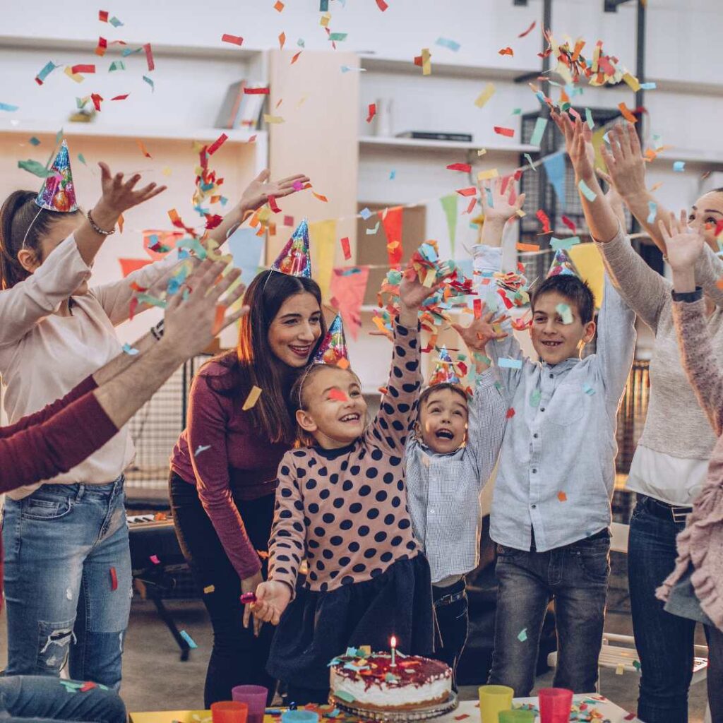 At a friend's birthday celebration, the guests pose for pictures while standing near the cake table,