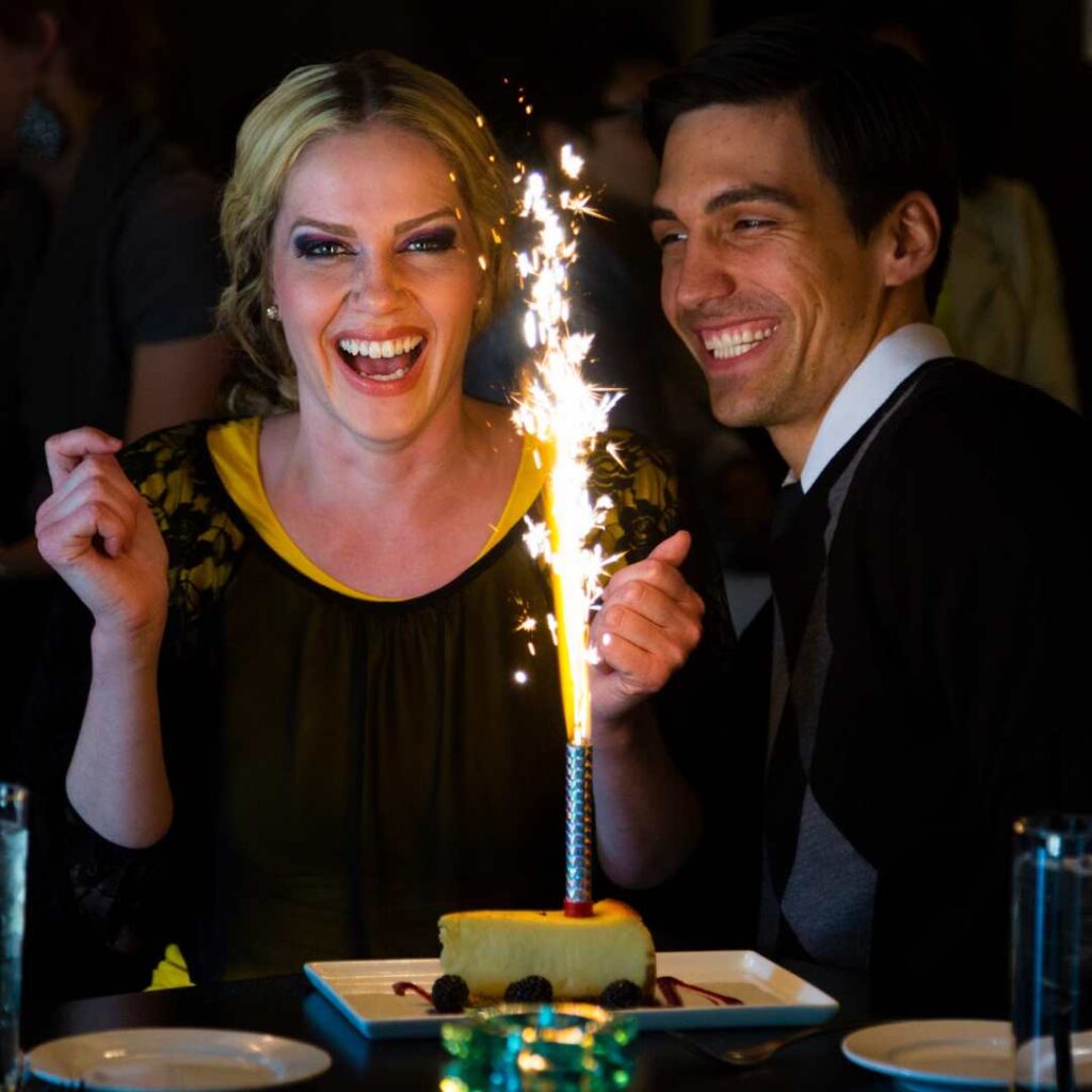 A youngÂ lady blowing out birthday candlesÂ with her mates while seated at the dining table - Happy 